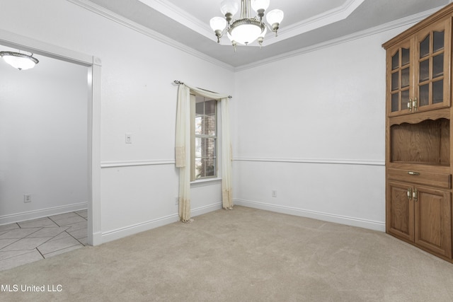 carpeted empty room featuring ornamental molding, an inviting chandelier, and a tray ceiling