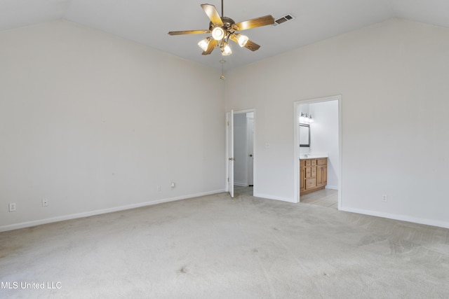 unfurnished bedroom featuring light colored carpet, vaulted ceiling, and ensuite bath