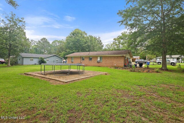 560 Bailey St, Mendenhall, MS 39114 - back of house featuring a lawn, a trampoline, and brick siding