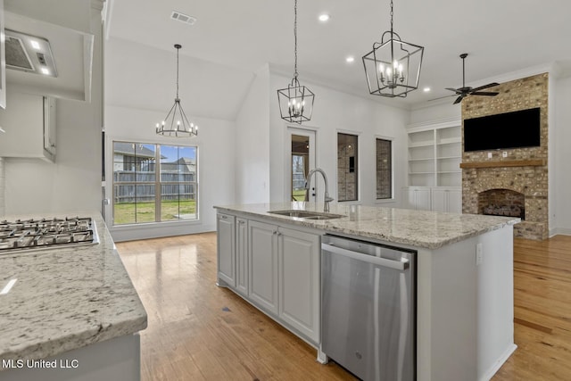 kitchen featuring a sink, visible vents, open floor plan, appliances with stainless steel finishes, and a brick fireplace