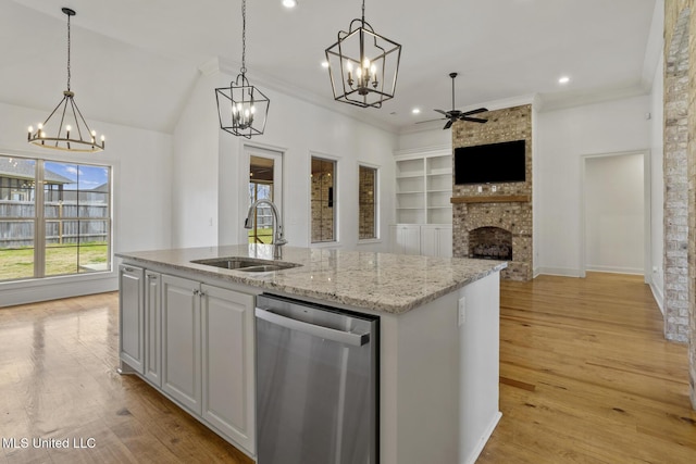 kitchen with light wood-type flooring, a brick fireplace, a sink, and stainless steel dishwasher