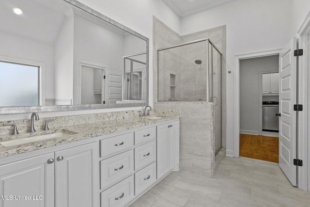 full bathroom featuring double vanity, a stall shower, and a sink