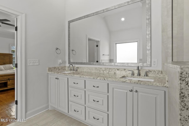 ensuite bathroom featuring ensuite bathroom, double vanity, a sink, and baseboards