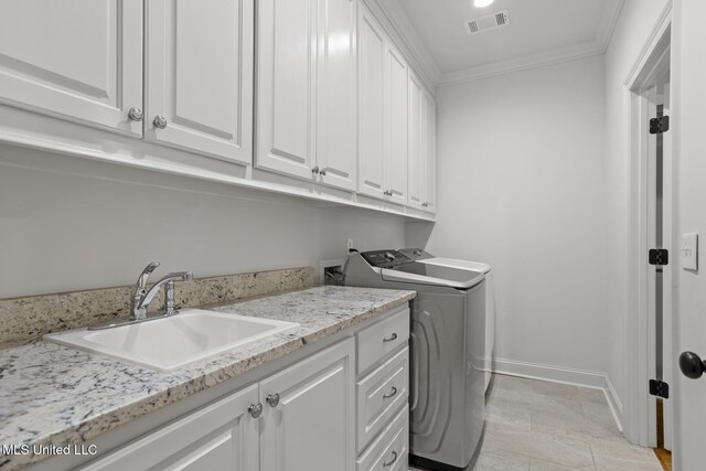 clothes washing area with cabinet space, visible vents, crown molding, separate washer and dryer, and a sink