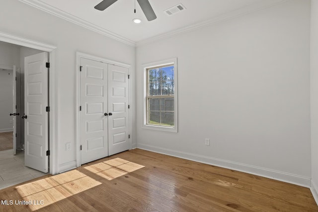 unfurnished bedroom with ornamental molding, light wood-style flooring, visible vents, and baseboards