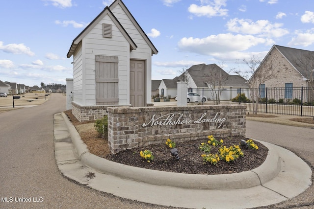 community / neighborhood sign featuring fence and a residential view