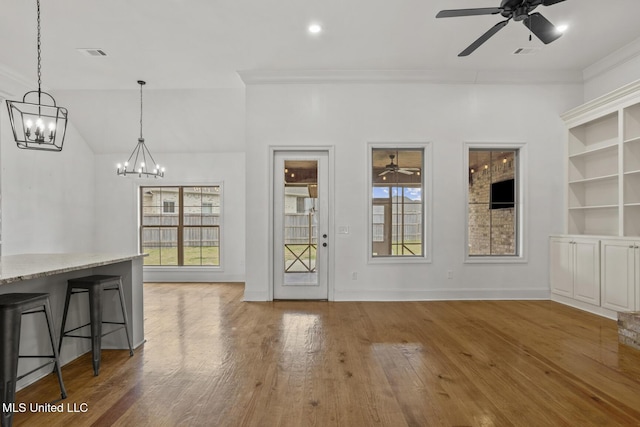 entrance foyer featuring ceiling fan with notable chandelier, visible vents, crown molding, and wood finished floors