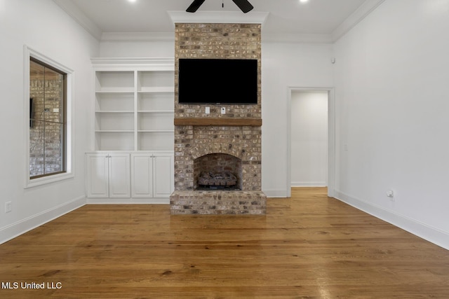 unfurnished living room featuring a fireplace, ornamental molding, and wood finished floors