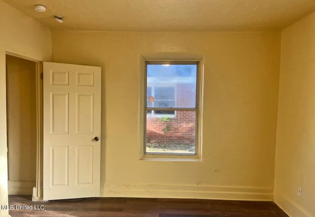 unfurnished room with a textured ceiling and dark hardwood / wood-style floors