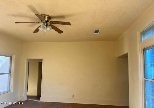 spare room featuring crown molding, dark hardwood / wood-style floors, a textured ceiling, and ceiling fan