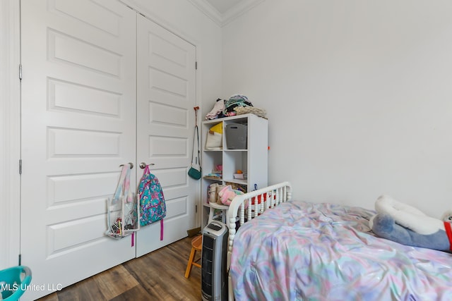 bedroom featuring crown molding, dark hardwood / wood-style floors, and a closet