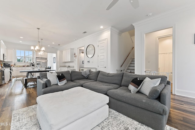 living room featuring ornamental molding, dark wood-type flooring, and ceiling fan with notable chandelier