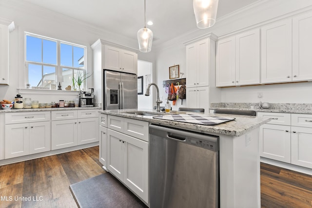 kitchen featuring white cabinetry, appliances with stainless steel finishes, decorative light fixtures, and a center island with sink