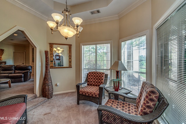 living area with crown molding, a raised ceiling, a chandelier, and light colored carpet