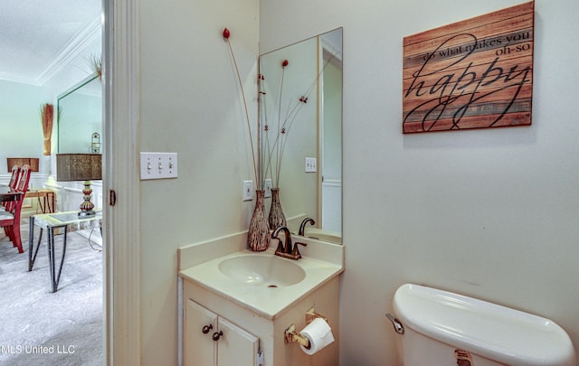 bathroom featuring toilet, ornamental molding, and a sink