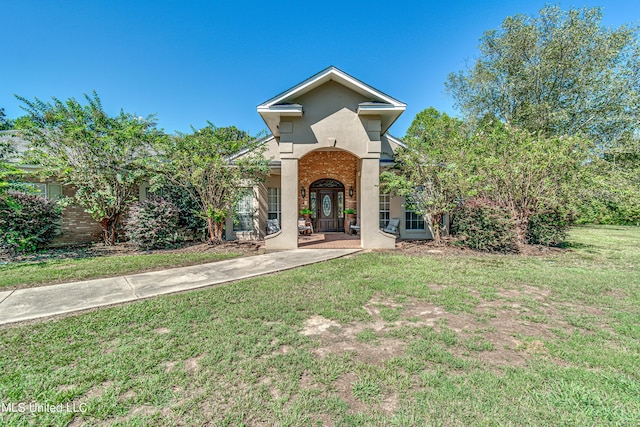 view of front of home featuring brick siding, a front yard, and stucco siding
