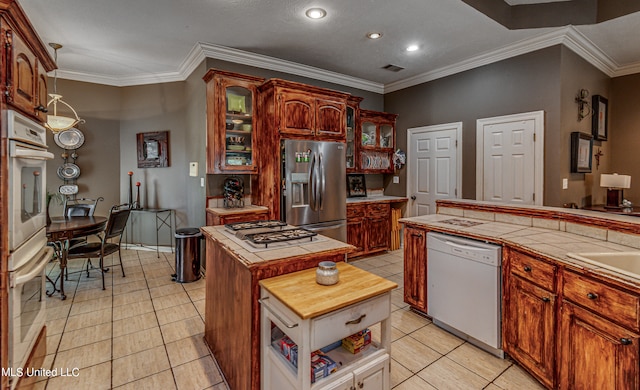 kitchen with a kitchen island, tile countertops, ornamental molding, light tile patterned floors, and appliances with stainless steel finishes