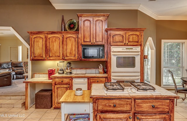 kitchen featuring light tile patterned flooring, tile counters, crown molding, and white appliances