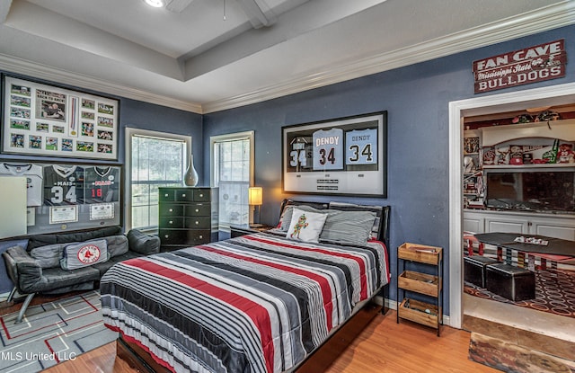 bedroom with a ceiling fan, crown molding, wood finished floors, and a raised ceiling