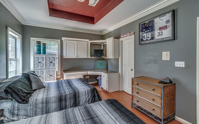 bedroom featuring light wood-style flooring, ornamental molding, and a raised ceiling