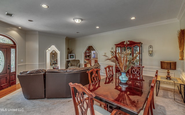 dining room with crown molding and light carpet