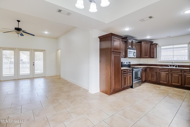 kitchen with dark brown cabinets, ceiling fan with notable chandelier, stainless steel appliances, sink, and light tile patterned floors