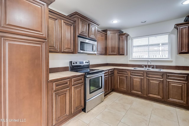 kitchen featuring light tile patterned flooring, appliances with stainless steel finishes, and sink