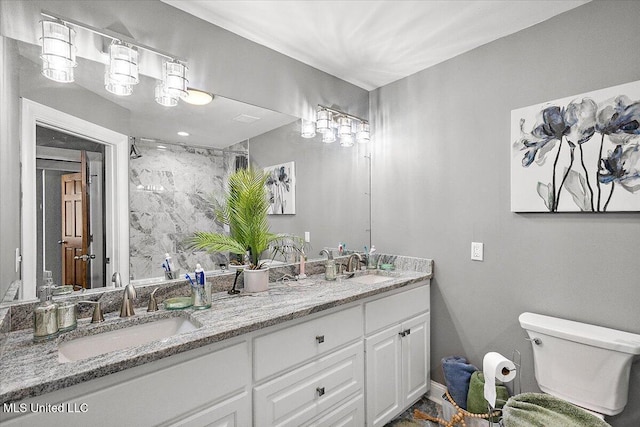 bathroom featuring vanity, tiled shower, and toilet