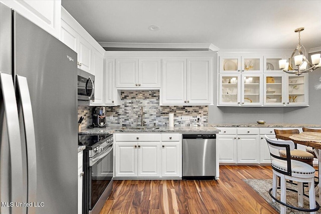 kitchen with sink, appliances with stainless steel finishes, white cabinetry, light stone countertops, and decorative light fixtures