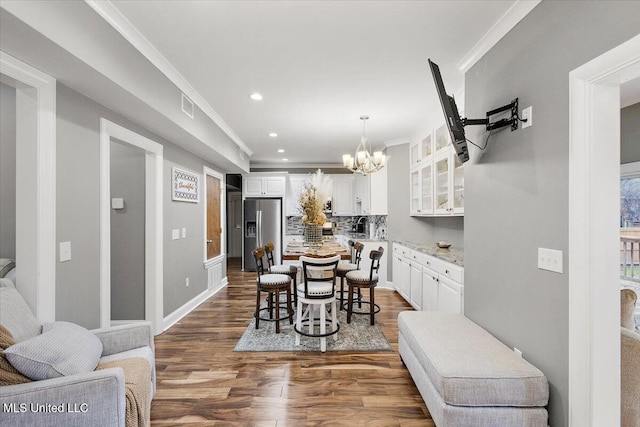 dining area featuring crown molding, a chandelier, and dark hardwood / wood-style flooring