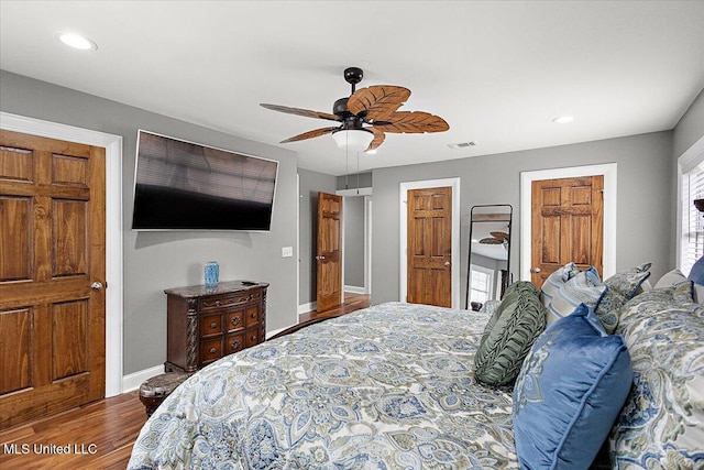 bedroom with wood-type flooring, two closets, and ceiling fan