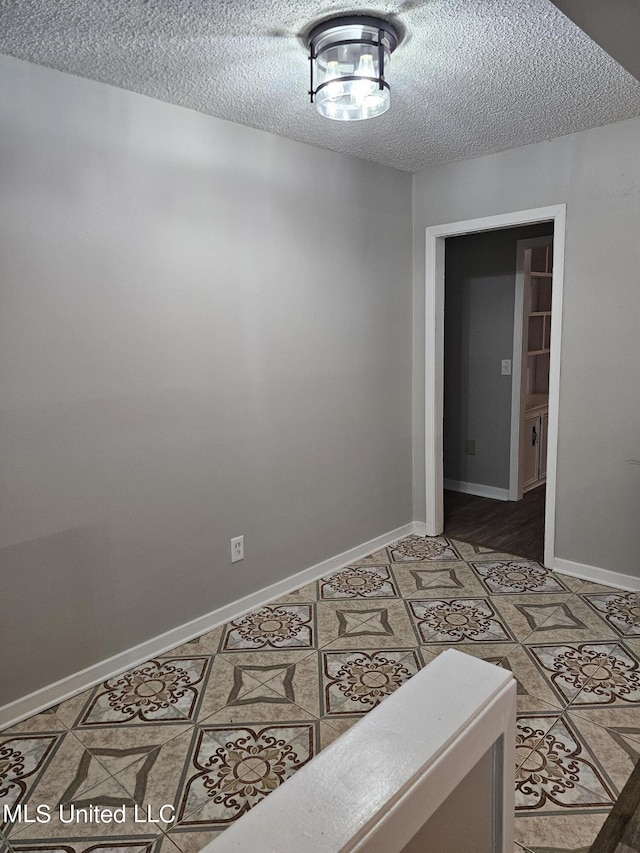 unfurnished room with light tile patterned floors, baseboards, and a textured ceiling