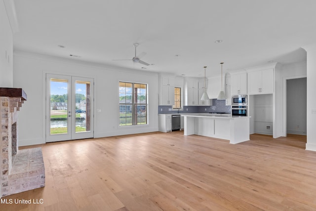 kitchen with a center island, decorative light fixtures, white cabinets, light hardwood / wood-style floors, and tasteful backsplash