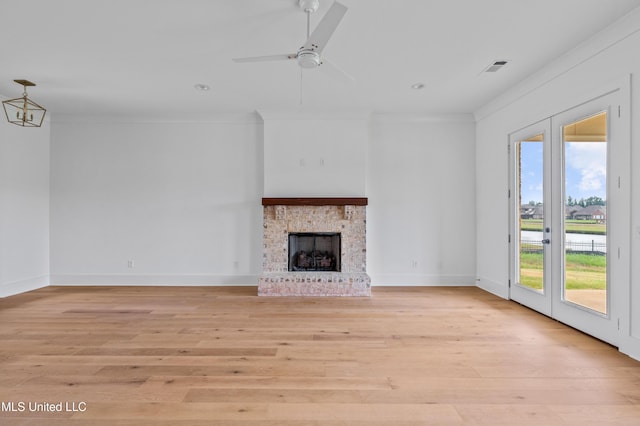 unfurnished living room with a ceiling fan, crown molding, a brick fireplace, and light wood finished floors