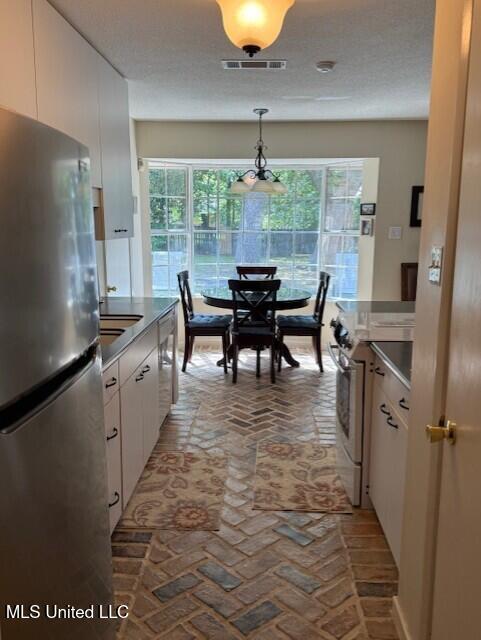 2246 Baywood Dr, Biloxi, MS 39532 - kitchen featuring appliances with stainless steel finishes, brick flooring, plenty of natural light, and white cabinetry