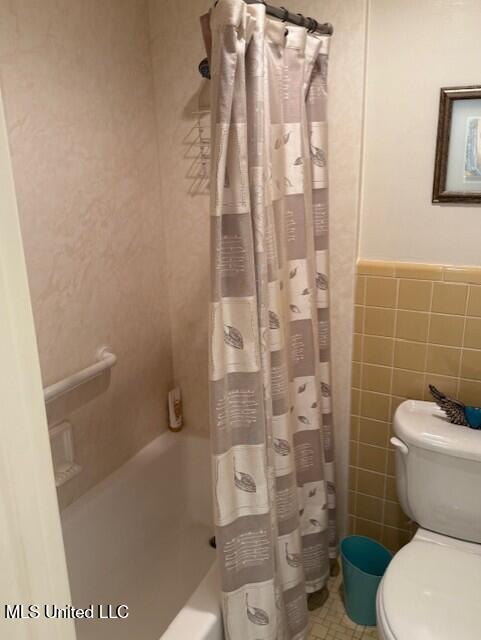 2246 Baywood Dr, Biloxi, MS 39532 - full bath with tile walls, toilet, shower / bath combo with shower curtain, and a wainscoted wall
