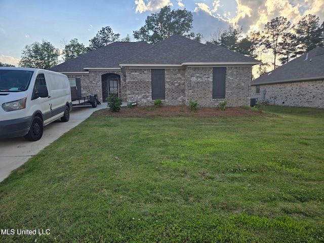 109 Brunswick Cv, Canton, MS 39046 - french country style house with brick siding, a shingled roof, a front yard, and central AC unit