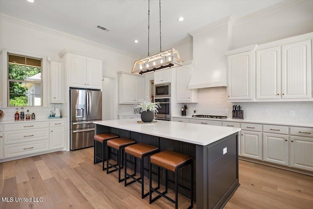 6603 Wirtz Rd, Flowood, MS 39232 - kitchen featuring stainless steel appliances, a kitchen breakfast bar, a kitchen island, white cabinetry, and ornamental molding