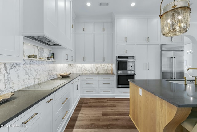 kitchen featuring pendant lighting, custom exhaust hood, stainless steel appliances, white cabinets, and a sink