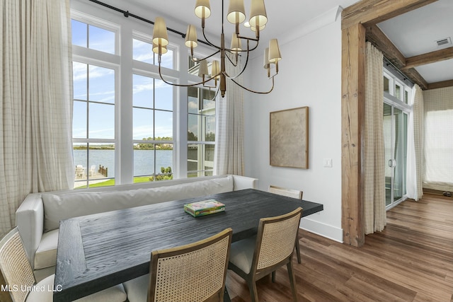 dining space with a wealth of natural light, a water view, a notable chandelier, and wood finished floors