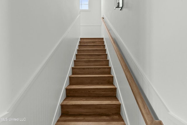 stairs featuring a wainscoted wall and a decorative wall