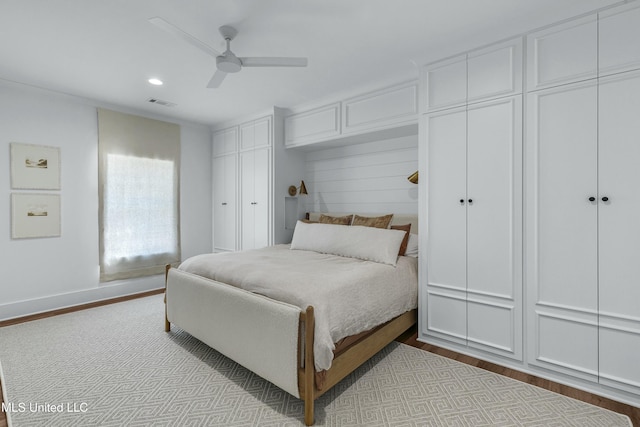 bedroom featuring recessed lighting, visible vents, a ceiling fan, light wood-type flooring, and two closets