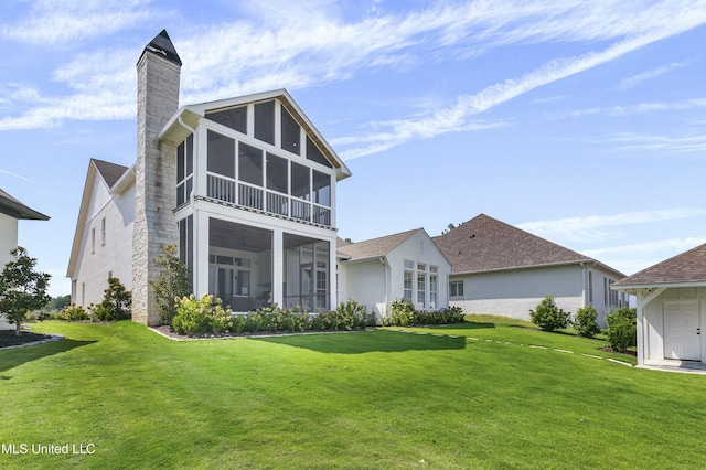 rear view of house with a sunroom, a lawn, and a chimney