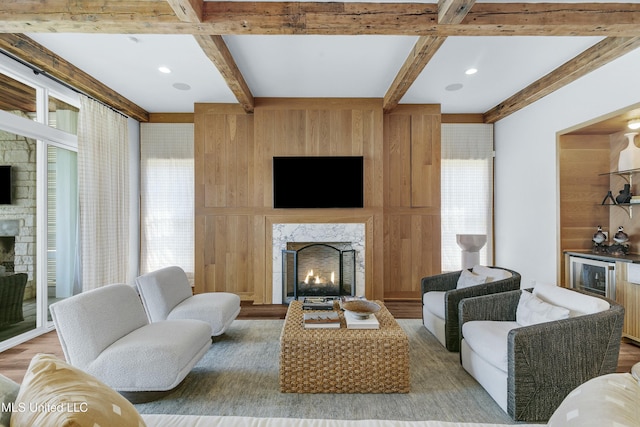 living room with a high end fireplace, beamed ceiling, a dry bar, and recessed lighting