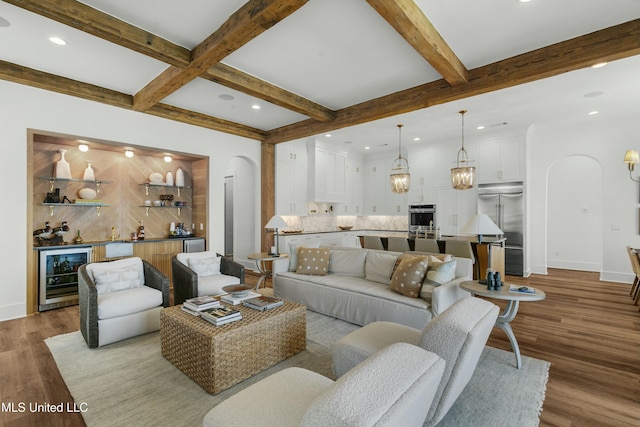 living area with arched walkways, wood finished floors, beverage cooler, beamed ceiling, and baseboards