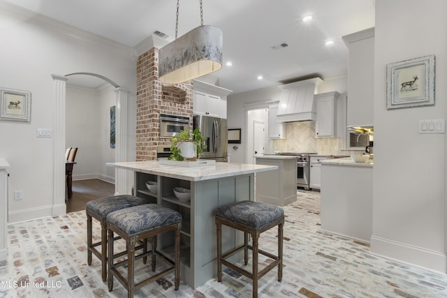 6416 Oliwa Pl, Diamondhead, MS 39525 - kitchen featuring appliances with stainless steel finishes, a center island, premium range hood, decorative backsplash, and a kitchen breakfast bar