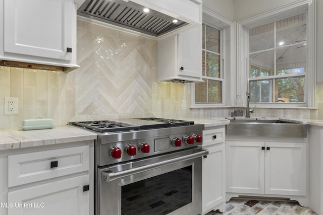 6416 Oliwa Pl, Diamondhead, MS 39525 - kitchen with premium stove, custom exhaust hood, white cabinetry, and light stone counters