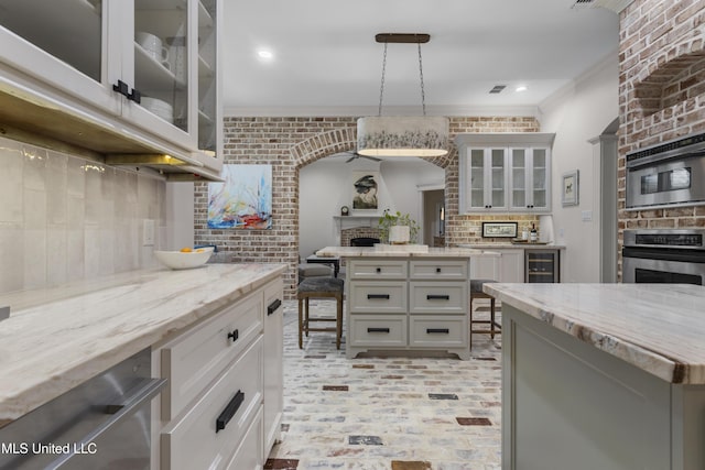 6416 Oliwa Pl, Diamondhead, MS 39525 - kitchen featuring stainless steel appliances, crown molding, decorative backsplash, brick wall, and a fireplace