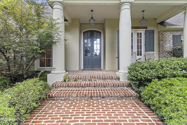 6416 Oliwa Pl, Diamondhead, MS 39525 - doorway to property featuring french doors, covered porch, stucco siding, and brick siding