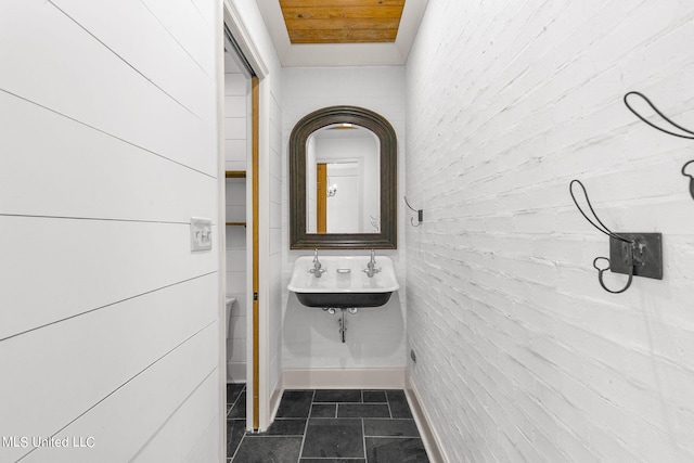 bathroom featuring brick wall, wooden ceiling, sink, and tile patterned floors